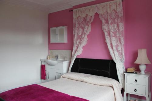 a bedroom with pink walls and a bed and a sink at Saint Gabriel's Road Guesthouse in London