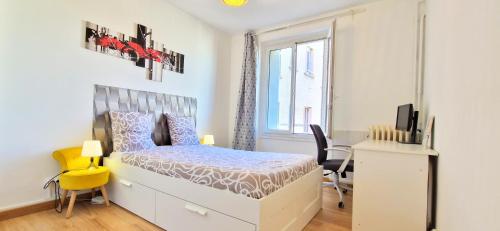1 dormitorio con 1 cama y escritorio con silla amarilla en Superbe appartement proche de toutes commodités., en Clermont-Ferrand