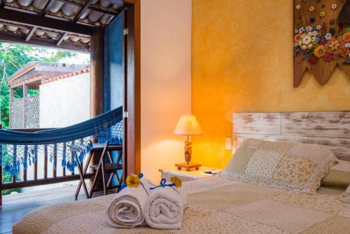 a bedroom with a bed and a balcony with a view at Pousada Rosa dos Ventos in Praia do Forte