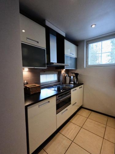 uma cozinha com armários brancos, uma pia e uma janela em Levin Kolmio C2 em Levi