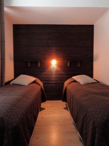 a bedroom with two beds and a wall with a light at Levin Kolmio C2 in Kittilä