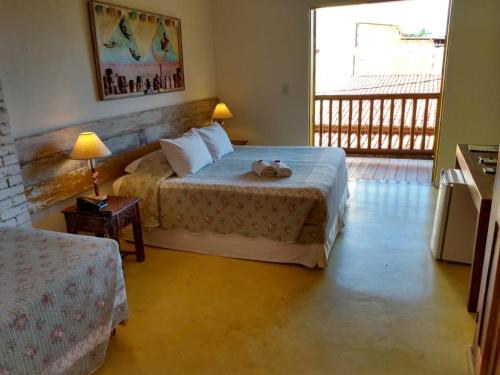 a hotel room with two beds and a balcony at Pousada Rosa dos Ventos in Praia do Forte