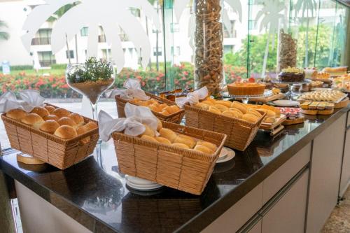 a buffet with baskets of bread and food on a counter at Marulhos Resort by Smart Stays in Porto De Galinhas