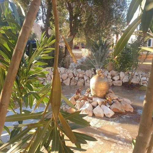 a garden with a large pot sitting on a pile of rocks at Hotel Pansy in Ksar Ghilane