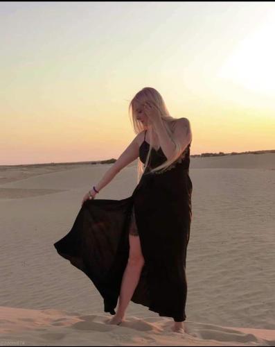 a woman in a dress walking on the beach at Hotel Pansy in Ksar Ghilane