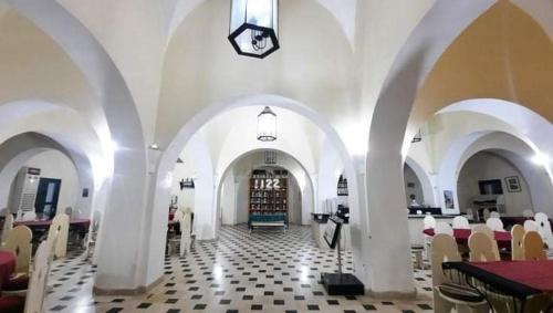 a room with white arches and tables and chairs at Hotel Pansy in Ksar Ghilane