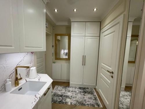 uma cozinha com armários brancos e um lavatório em ART Uzupis Apartment in City center em Vilnius