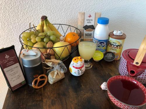 a table with a basket of fruit and a glass of juice at Cosy-Adventure : Haguenau in Haguenau