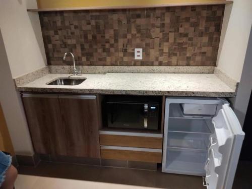 a small kitchen with a sink and a microwave at Solar das Águas Resort in Olímpia