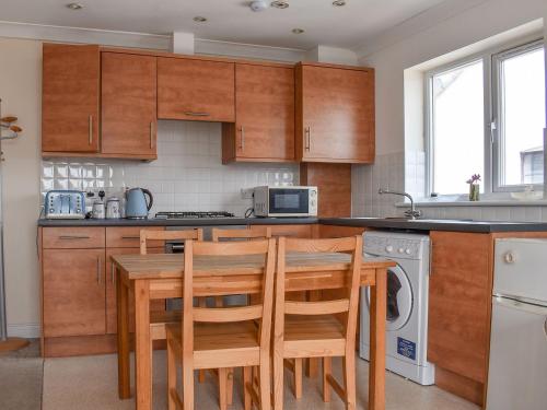 a kitchen with wooden cabinets and a table and chairs at Atlas And Pearl in South Hayling