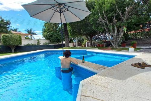 a man is in a swimming pool with an umbrella at Casa del Ancla Santa fe Social Golf Club in Cuernavaca