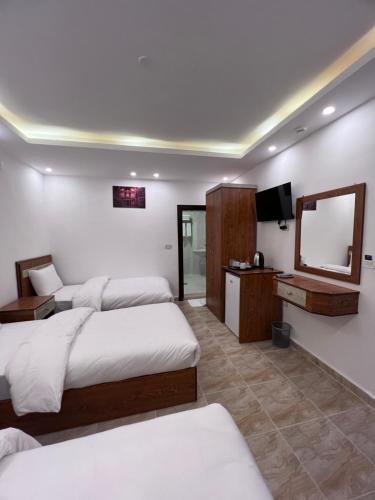a bedroom with two beds and a mirror at Petra Family Hotel in Wadi Musa