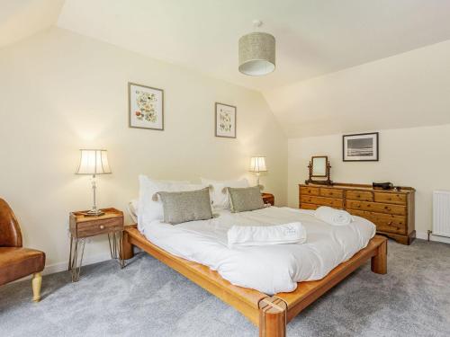 a bedroom with a large white bed and a chair at New Cottage in Farr