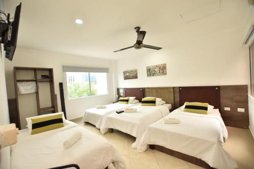 a room with three beds and a ceiling fan at Hotel La Casa N. 3 in Montería