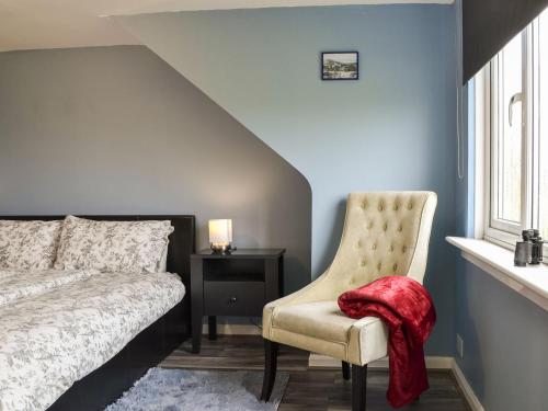 a bedroom with a bed and a chair and a window at Greve Cottage in Marykirk