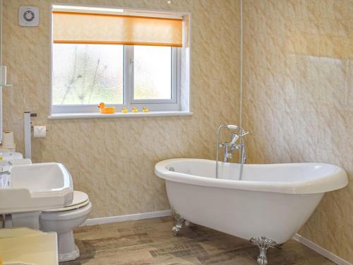 baño con bañera, aseo y ventana en Wild Lupin, en Kessingland