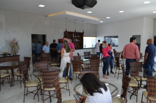 a group of people standing in a room with tables and chairs at HOTEL IMPERIO in Aparecida do Taboado