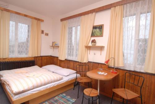 a small bedroom with a bed and a table at Horský Hotel Arnica in Loučná pod Klínovcem