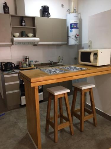 a kitchen with a counter with a microwave and two stools at Real .Departamento in Luján