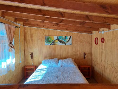 a bedroom with a bed with a wooden wall at Borde Mar, Hostal & Cabañas, Bahía Mansa in Bahía Mansa