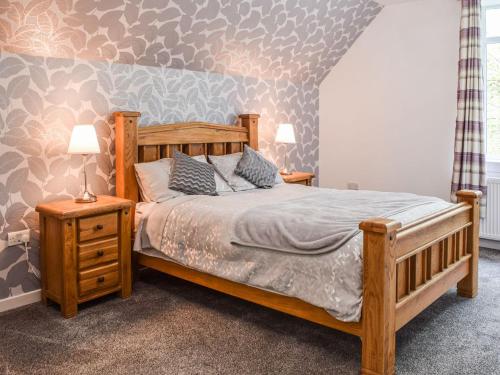 a bedroom with a wooden bed and two night stands at Gleaner Lea in Campbeltown