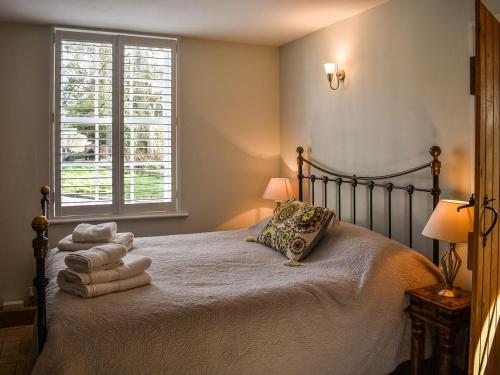 a bedroom with a bed with towels and a window at May Cottage in Rendham