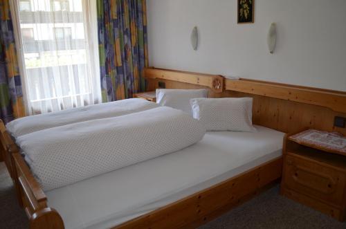 a large white bed in a room with a window at Lärchenhof in Leutasch