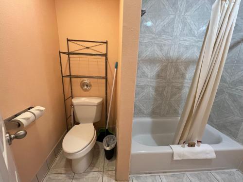 a bathroom with a toilet and a tub and a shower at Frazier View Motel in Frazier Park