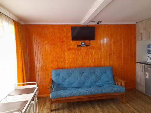 sala de estar con sofá azul y TV en Hostal Vicencio - Mini Departamentos, en Iquique