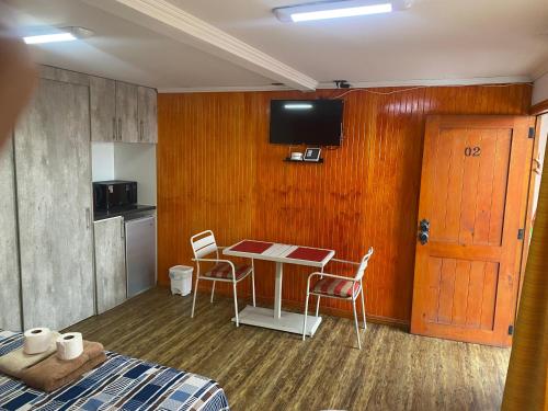 a room with a table and chairs and a kitchen at Apart Hotel Vicencio Iquique in Iquique