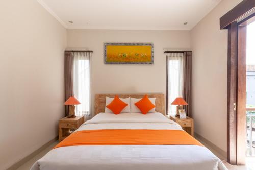 Un dormitorio con una cama grande con almohadas naranjas. en Rumah Kultur, en Ubud
