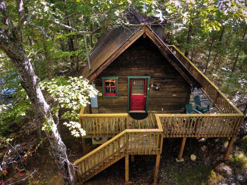 uma cabina de madeira com um deque e uma porta vermelha em Gatlinburg Adventure Cabins em Sevierville