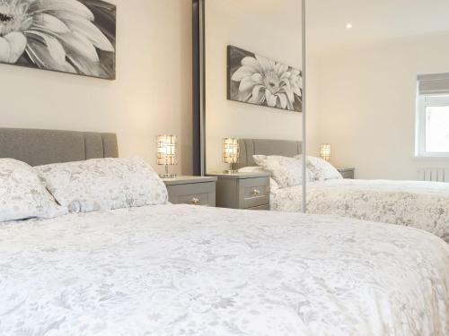 a bedroom with two beds and a mirror at Princess Court Apartment in Llanelli