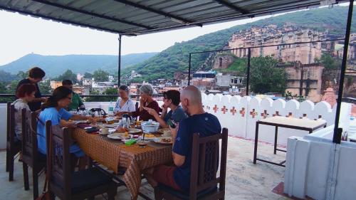 Eine Gruppe von Menschen, die an einem Tisch sitzen und Essen essen. in der Unterkunft Bundi Inn - A Heritage Boutique Haveli in Bundi