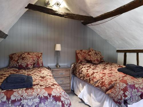 a bedroom with two beds and a lamp in a attic at Brushmaker Cottage in Diss