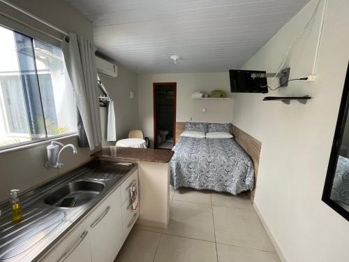uma pequena cozinha com um lavatório e uma cama em Pousada Marques Floripa em Florianópolis