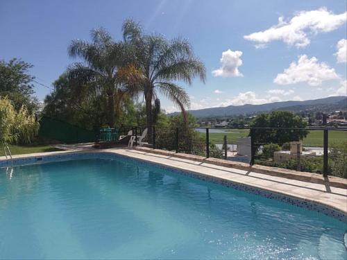 een groot blauw zwembad met een hek en palmbomen bij InterLaken Apart & Suites in Villa Carlos Paz