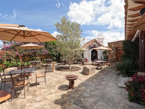 a patio with tables and chairs and an umbrella at Hotel Boutique El Carmel in Villa de Leyva