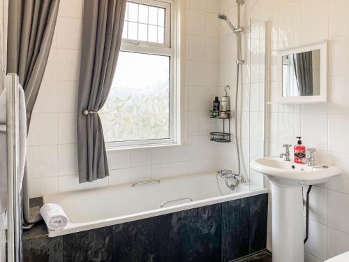 a bathroom with a tub and a sink and a window at The Garden House in Folkestone