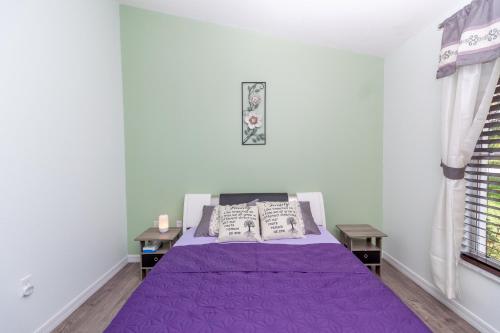 1 dormitorio con 1 cama de color púrpura y 2 mesas en Gorgeous Fully Furnished 2-Bedroom Luxury Villa, en Kissimmee