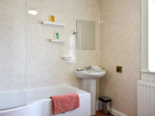 a bathroom with a sink and a bath tub and a sink at Old Stables Cottage in Hunwick