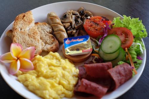 a plate of breakfast food with eggs meat and vegetables at Bali Wirasana Inn in Sanur
