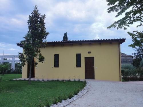 una pequeña casa amarilla con un árbol delante en B&B Da Fiorò, en Massignano