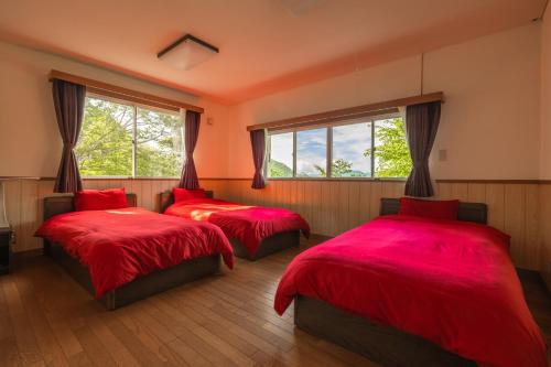 - 2 lits dans une chambre dotée de draps rouges et de fenêtres dans l'établissement Kanra-gun - House / Vacation STAY 2833, à Karuizawa