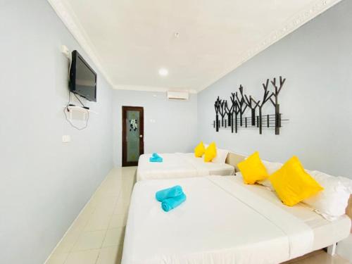 two white beds in a white room with a tv at FAT MERMAID GUESTHOUSE in Pantai Cenang