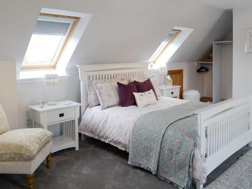 Un dormitorio con una cama blanca con almohadas y una ventana en Rose Cottage en Dingwall