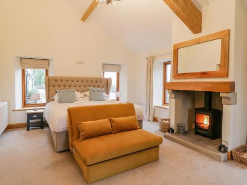 a bedroom with a bed and a fireplace and a chair at Coppa Hill Barn in Carnforth