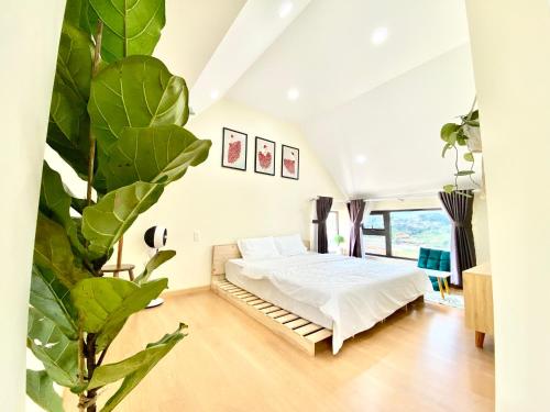a bedroom with a bed and a large plant at Bảo Châu Villa & Coffee Đà Lạt in Da Lat