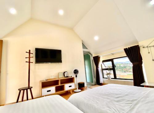 a bedroom with two beds and a tv on the wall at Bảo Châu Villa & Coffee Đà Lạt in Da Lat