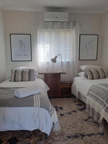 a bedroom with two beds and a lamp and a window at Sterrenhemel Guest Farm in Upington